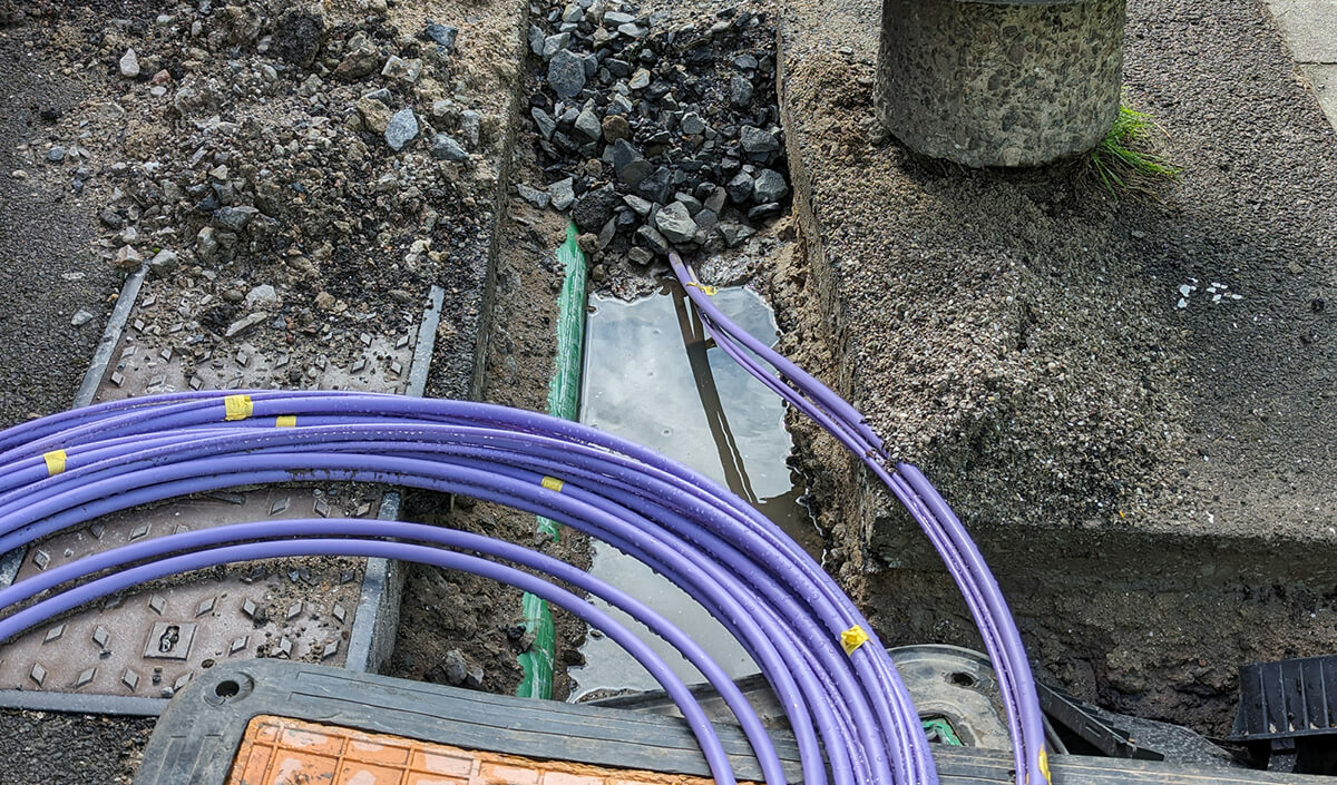 Fibre optic cable coming out of a trench curled up waiting to be installed for the UK gigabit broadband rollout being installed by the internet service providers ISPs across the country.